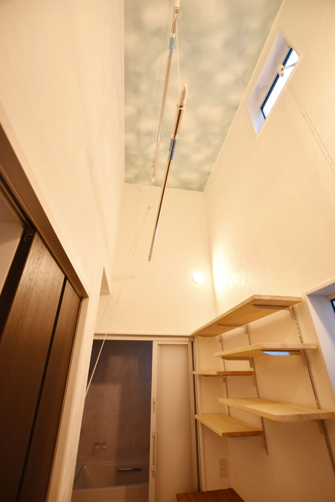 一階でも天井高を上げて室内物干しを設置しました。お空みたいな天井壁紙がいい感じです。
